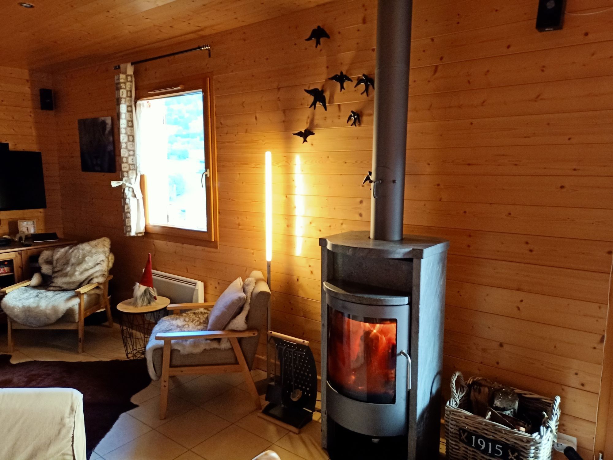 Un intérieur de chalet chaleureux avec un poêle à bois, une télévision et un coin salon confortable.