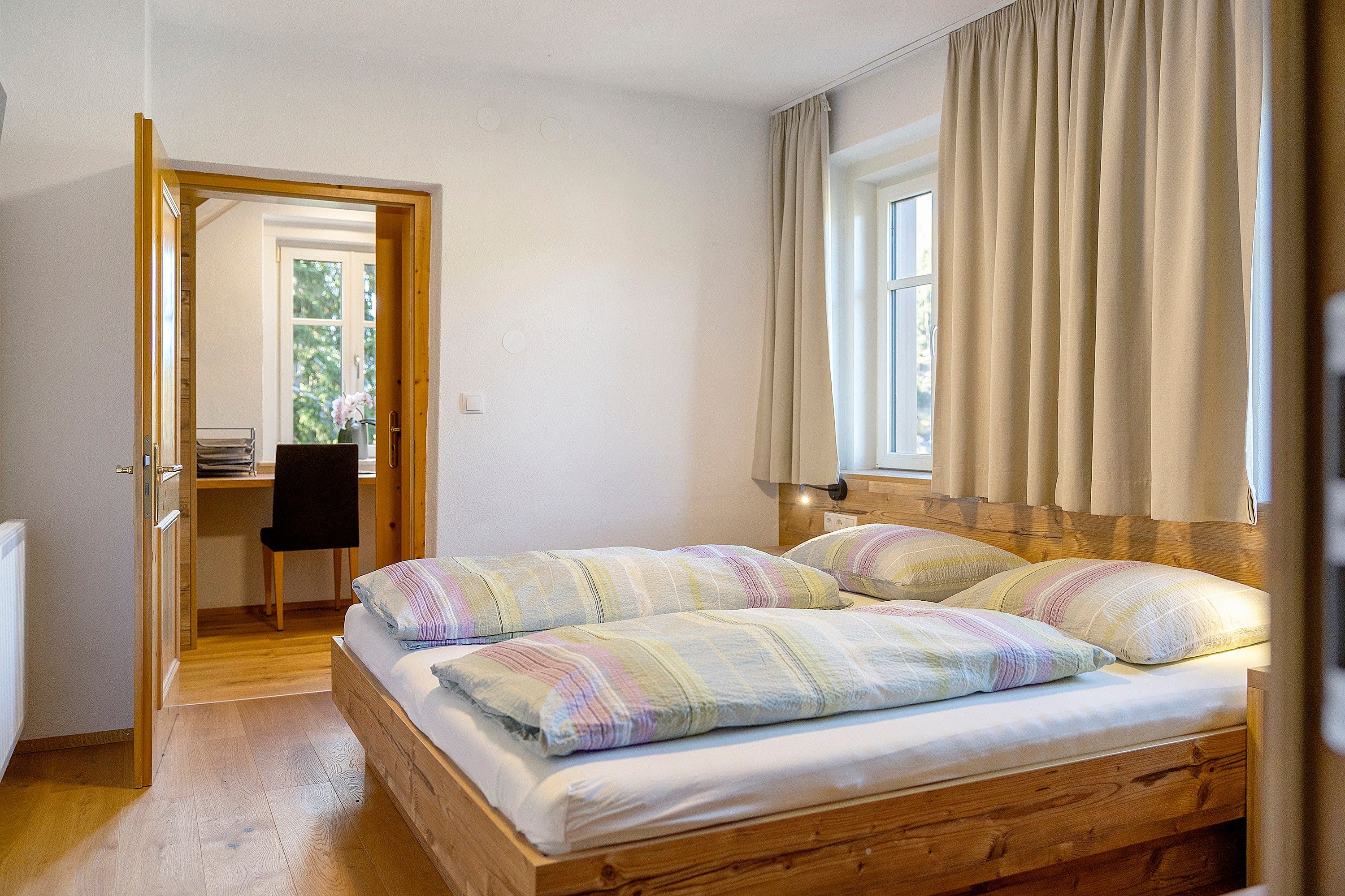 Ein Schlafzimmer mit einem hölzernen Bett, einem Schreibtisch und einem Stuhl.