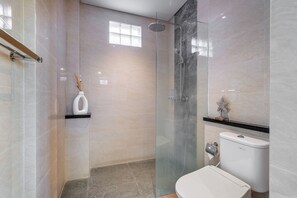 A modern bathroom with a glass-enclosed shower, a toilet, and a shelf with a decorative item. - Chic 2BR Private Pool Villa Seminyak, Enclosed AC Living & Fast Wi-Fi (Badung)