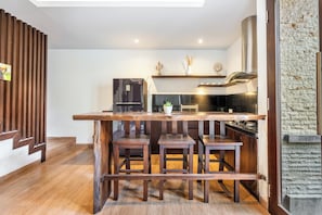 A modern kitchen with a wooden bar area, a refrigerator, and a stove. - Chic 2BR Private Pool Villa Seminyak, Enclosed AC Living & Fast Wi-Fi (Badung)