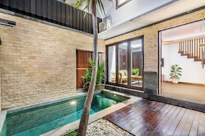 A modern house with a swimming pool, a wooden deck, and a staircase leading to an upper level. - Chic 2BR Private Pool Villa Seminyak, Enclosed AC Living & Fast Wi-Fi (Badung)