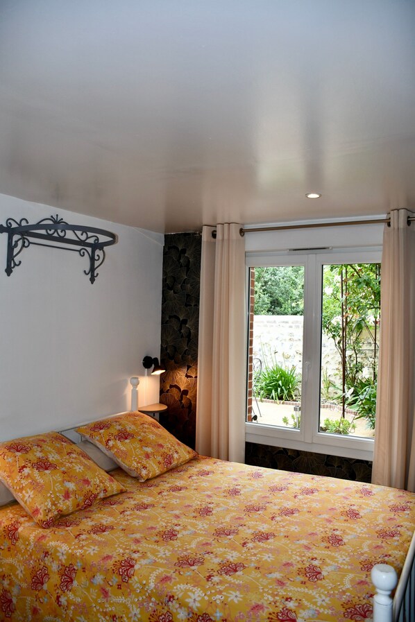 Ein Schlafzimmer mit einem Bett, einer Wandleuchte und einem Fenster mit Vorhängen.
