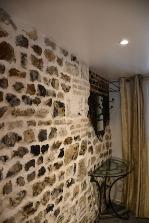 Ein Zimmer mit Steinwand, Glastisch und Vorhang.
