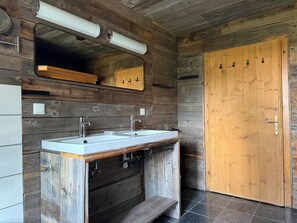 Une salle de bain avec des murs en bois, une porte en bois et un lavabo équipé de deux robinets.