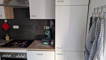 A compact kitchen with a stove, oven, and a coffee maker on the countertop.