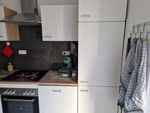 A compact kitchen with a stove, oven, and a coffee maker on the countertop. - Holiday Apartment 'Lucy' with Shared Terrace, Shared Garden and Wi-Fi (Nattenheim)