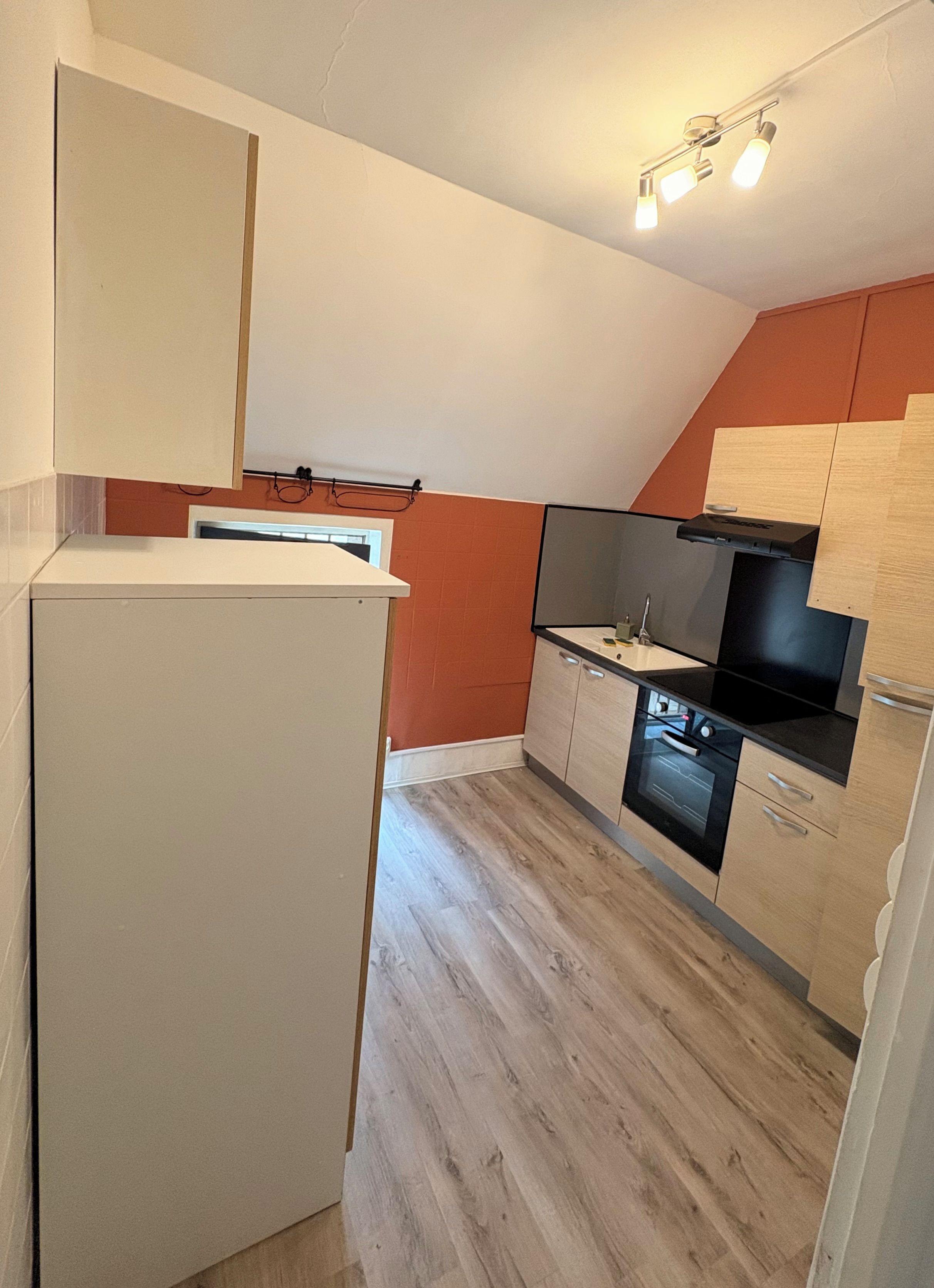 Cocina compacta con refrigerador, estufa, horno y gabinetes de madera.
