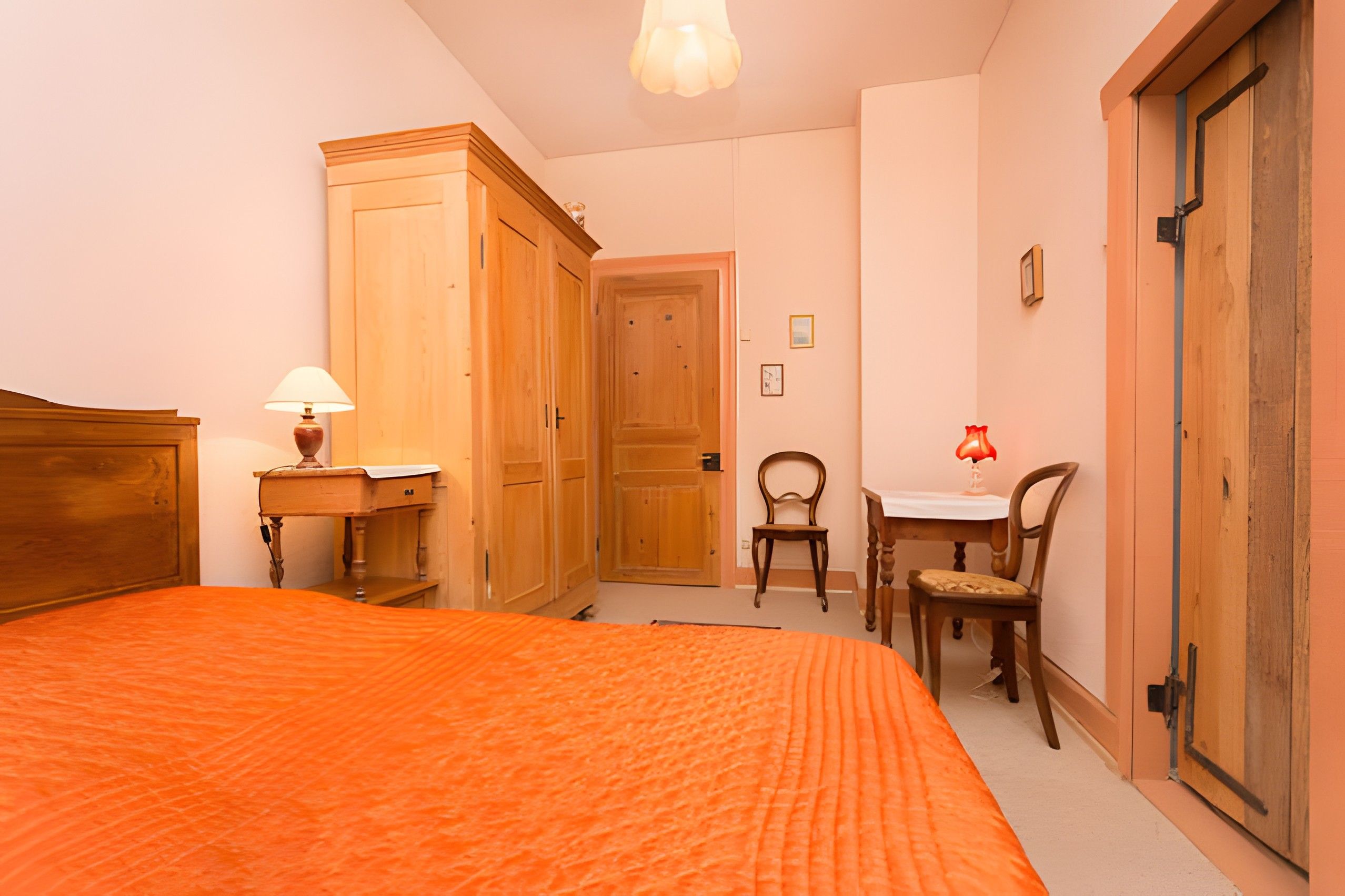 A bedroom with a bed, a desk, a chair, and a wardrobe.