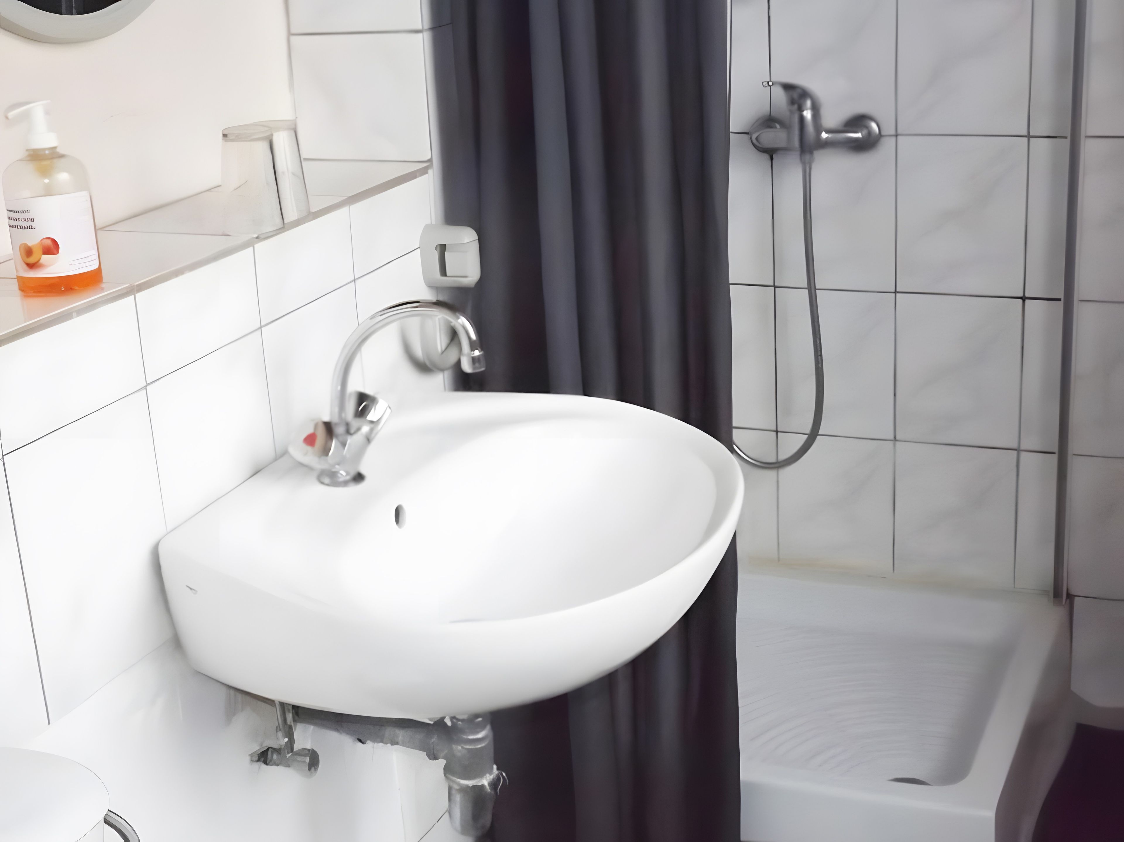 A bathroom with a white sink, a shower, and a toilet.