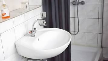 A bathroom with a white sink, a shower, and a toilet.