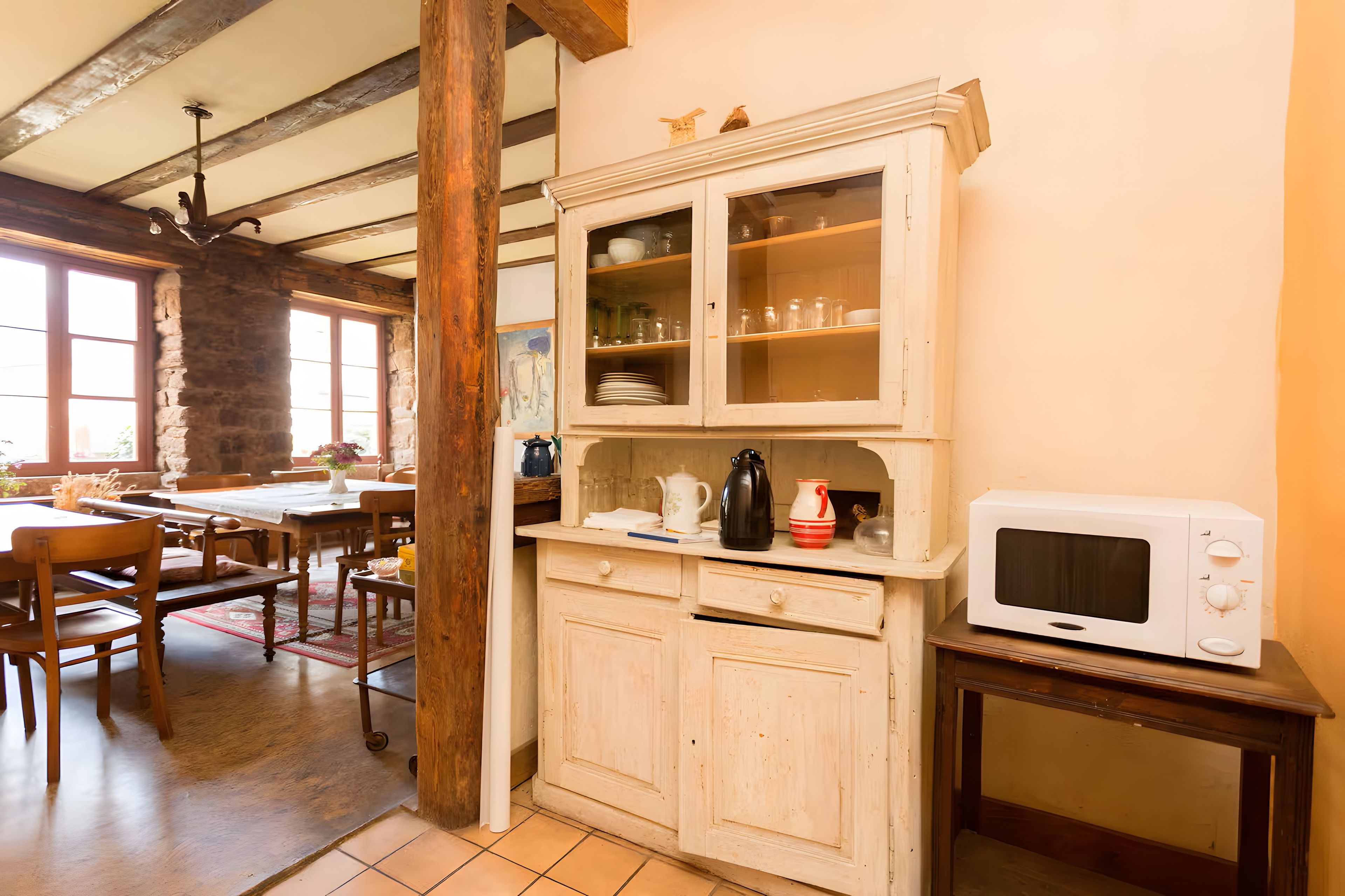 A kitchen with wooden cabinets, a microwave, and a dining area with wooden chairs and a table.