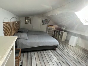 Ein Schlafzimmer mit einem Bett, einer Holzleiter, einem weißen Schrank und einem Deckenventilator.
