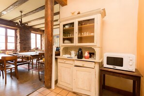 A kitchen with wooden cabinets, a microwave, and a dining area with wooden chairs and a table. - Bed and Breakfast 'Chambre Familiale' with Mountain View, Shared Terrace and Wi-Fi (Thannenkirch)