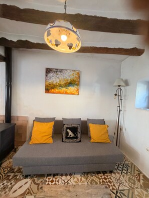 Una habitación con sofá, un cuadro, una lámpara y suelo estampado.