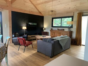 Uma sala de estar moderna com lareira, televisão e área de jantar com mesa e cadeiras.