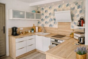 A compact kitchen with a built-in oven, a coffee maker, and a kettle on the counter. - New Listing (Jonquières)