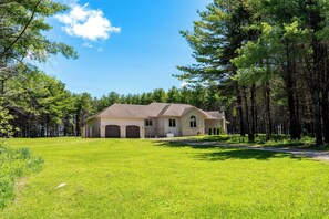 A single-story house with a large front lawn, a garage, and a detached garage.