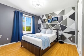 A modern bedroom with a bed, curtains, a geometric wall design, and a star-shaped ceiling light.