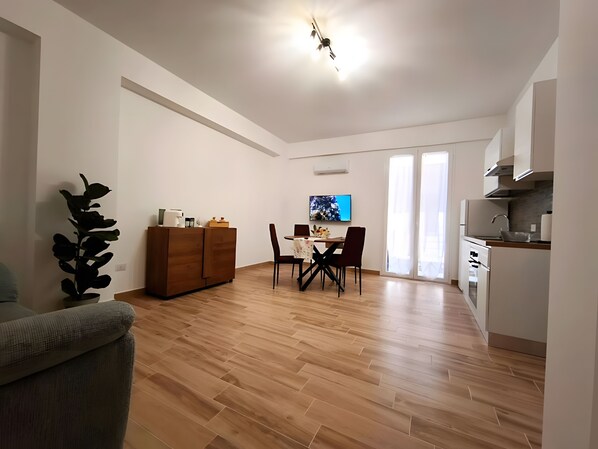 Een modern appartement met een eethoek, keuken en een groot raam.