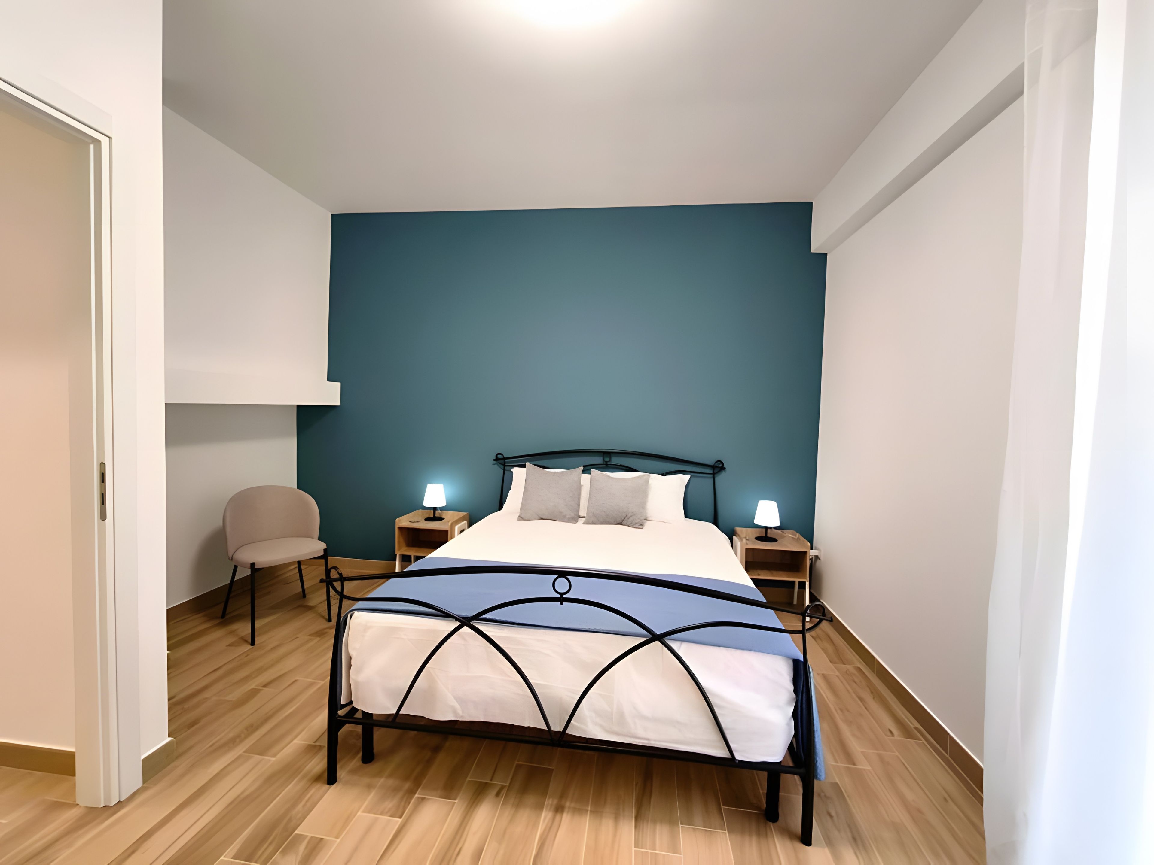 A bedroom with a bed, bedside tables, a chair, and a nightstand.