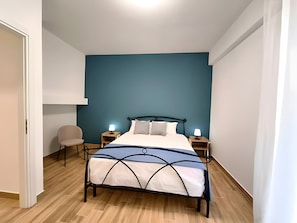 Een slaapkamer met een bed, nachtkastjes, een stoel en een bedbank.