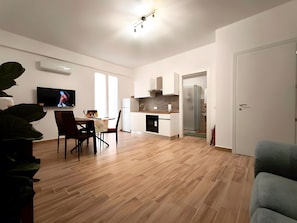 Een moderne woonruimte met een eethoek, keuken en televisie.