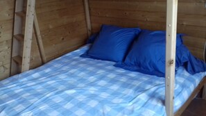 Un lit simple avec une couvre-lit à carreaux bleus et blancs et deux oreillers bleus.