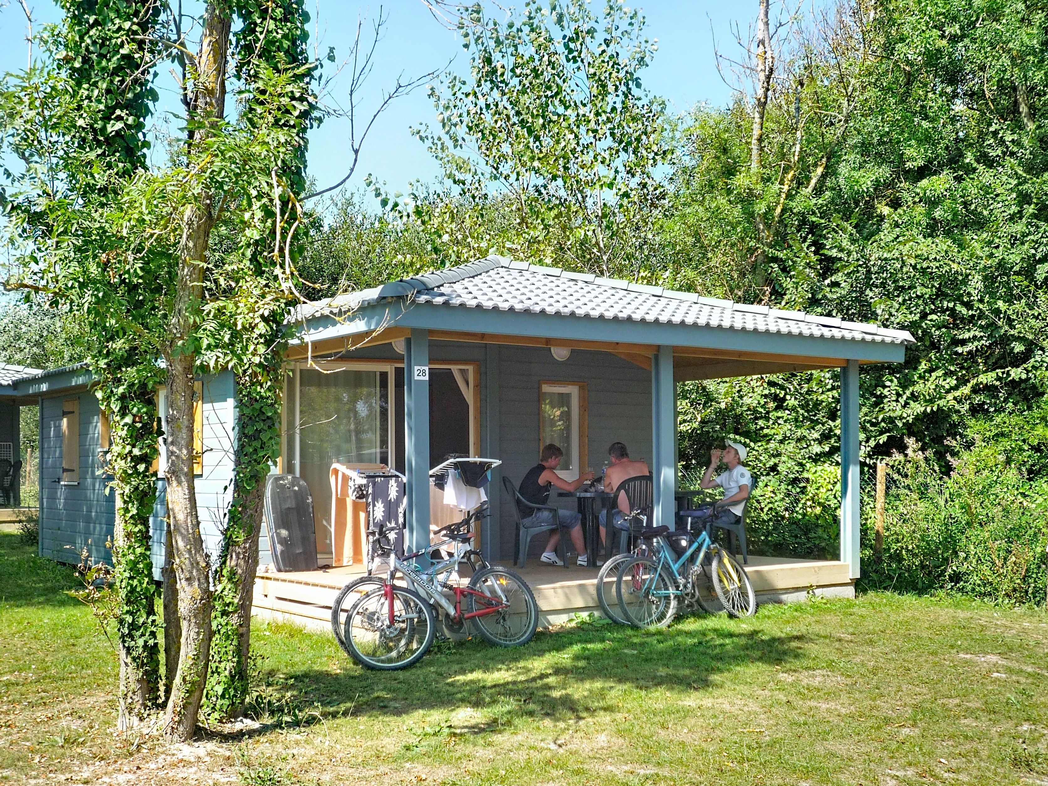 A small, single-story building with a porch, a covered seating area, and bicycles parked outside.