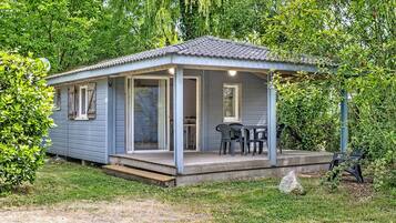 A small, single-story cabin with a porch, a dining table, and chairs.