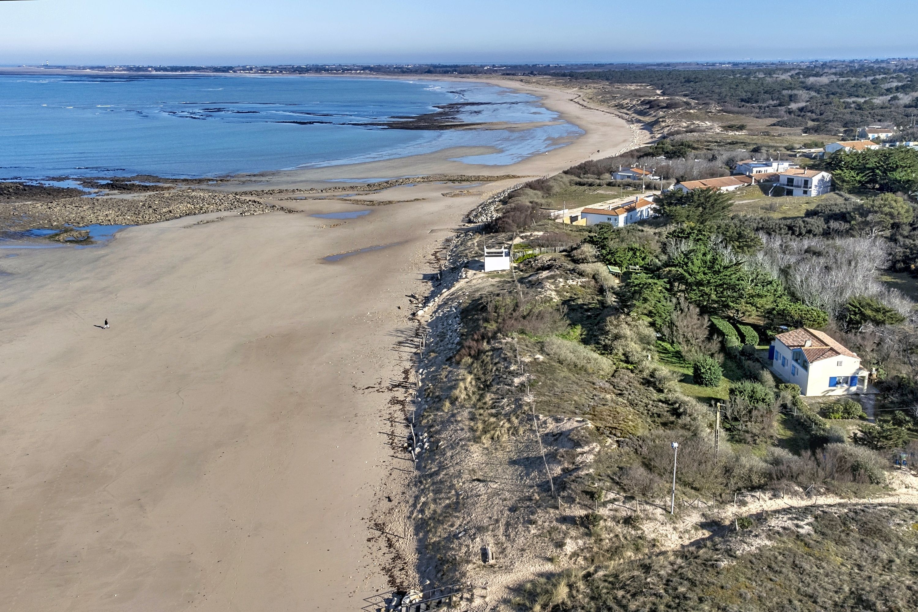 A coastal property with a sandy beach, a rocky shoreline, and a residential area with houses.