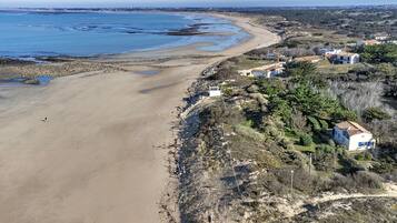 A coastal property with a sandy beach, a rocky shoreline, and a residential area with houses.