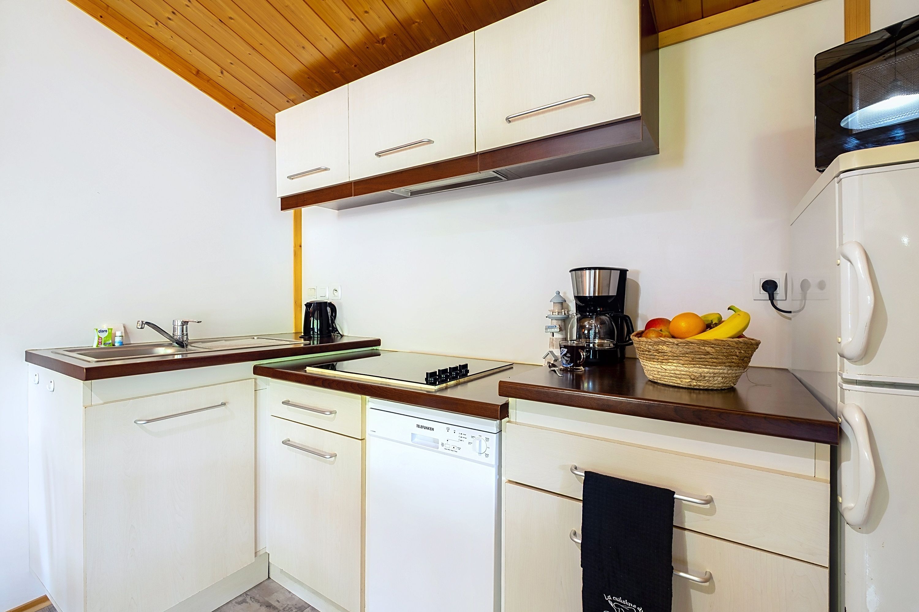 A kitchen with white cabinets, a wooden countertop, a coffee maker, and a fruit basket.