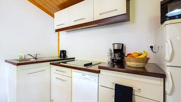 A kitchen with white cabinets, a wooden countertop, a coffee maker, and a fruit basket.