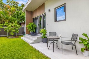 Une maison moderne dotée d’un patio, d’une petite table, de deux chaises et de plantes en pot.