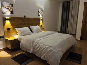Ein ordentlich bezogenes Bett mit weißer Bettwäsche und zwei Nachttischlampen.