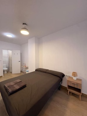 A bedroom with a bed, bedside table, and a lamp. - Cami Real Hostel (Port de Sagunt)