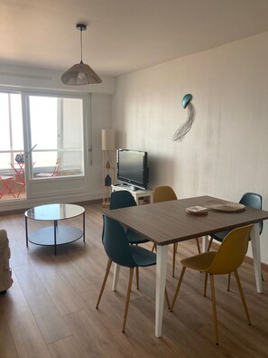 Spiseområde med et træbord, stole, et fjernsyn og et vindue med udsigt.