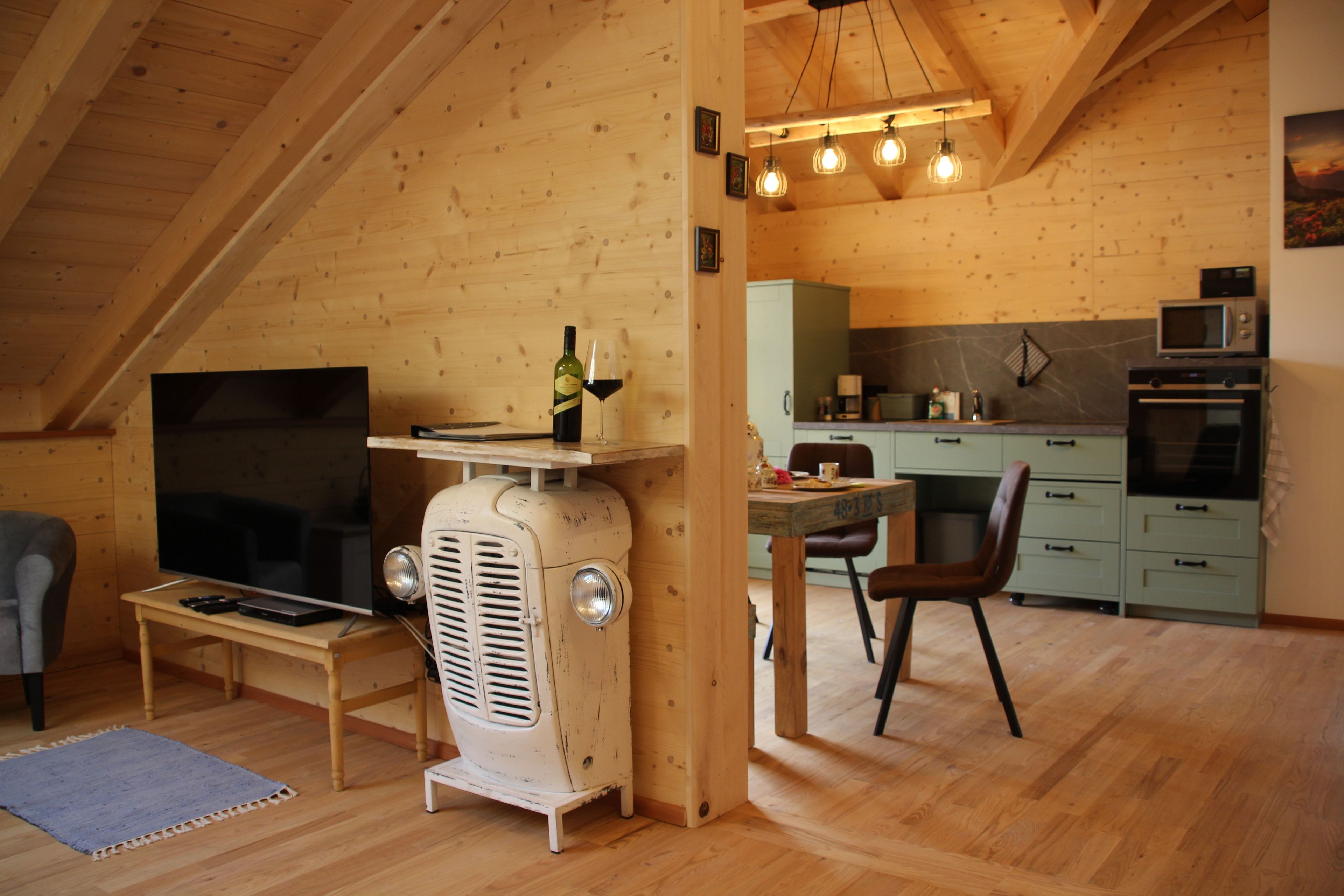 Ein gemütliches Holzinterieur mit Essbereich, einem Vintage-Radio und einer Küche mit modernen Geräten.