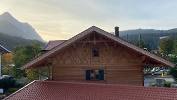 Eine Holzhütte mit steilem Dach, einem kleinen Fenster und einem Schornstein.