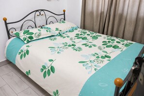 A bed with a floral bedspread, a wooden headboard, and a curtain. - Cozy 1-bedroom apartment in beautiful Accra with AC (Accra)