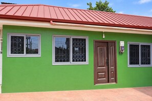 A building with a green facade, a red roof, and a brown door. - Cozy 1-bedroom apartment in beautiful Accra with AC (Accra)