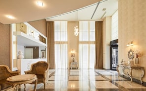 Un vestíbulo amplio con piso de cuadros, muebles elegantes y un gran espejo que refleja la estancia.