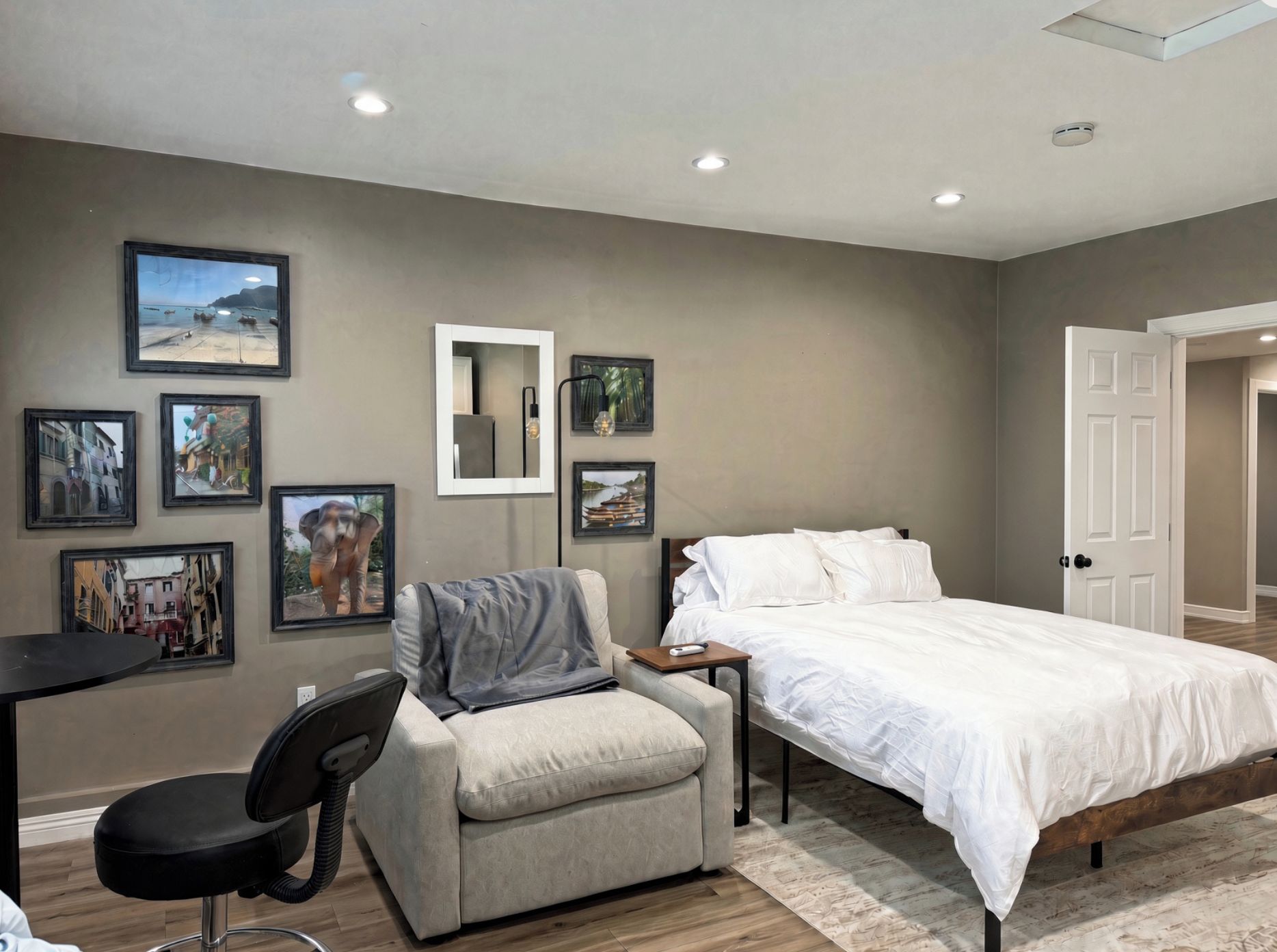 Une chambre à coucher avec un lit, une chaise, un bureau et plusieurs tableaux encadrés accrochés au mur.