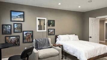 Une chambre à coucher avec un lit, une chaise, un bureau et plusieurs tableaux encadrés accrochés au mur.