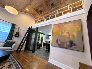 Un salon moderne avec un plafond en bois, un coin repas et une cuisine à l’arrière-plan.