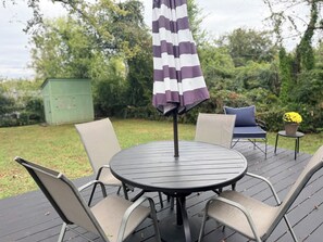 Une table ronde en métal, quatre chaises, un parasol et une petite table sur laquelle est posée une plante en pot.