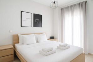 A modern hotel room with a neatly made bed, two bedside tables, a laptop, and a window with curtains. - 2-bedroom apartment in Thessaloniki (Pylaia). Sleeps 5. Pet-friendly! (Pilea)