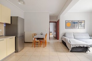 A compact living space with a kitchenette, a dining area, and a sofa. - 2-bedroom apartment in Thessaloniki (Pylaia). Sleeps 5. Pet-friendly! (Pilea)