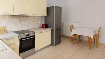 Une cuisine compacte équipée d’une cuisinière, d’un four, d’un réfrigérateur et d’une table à manger avec des chaises.