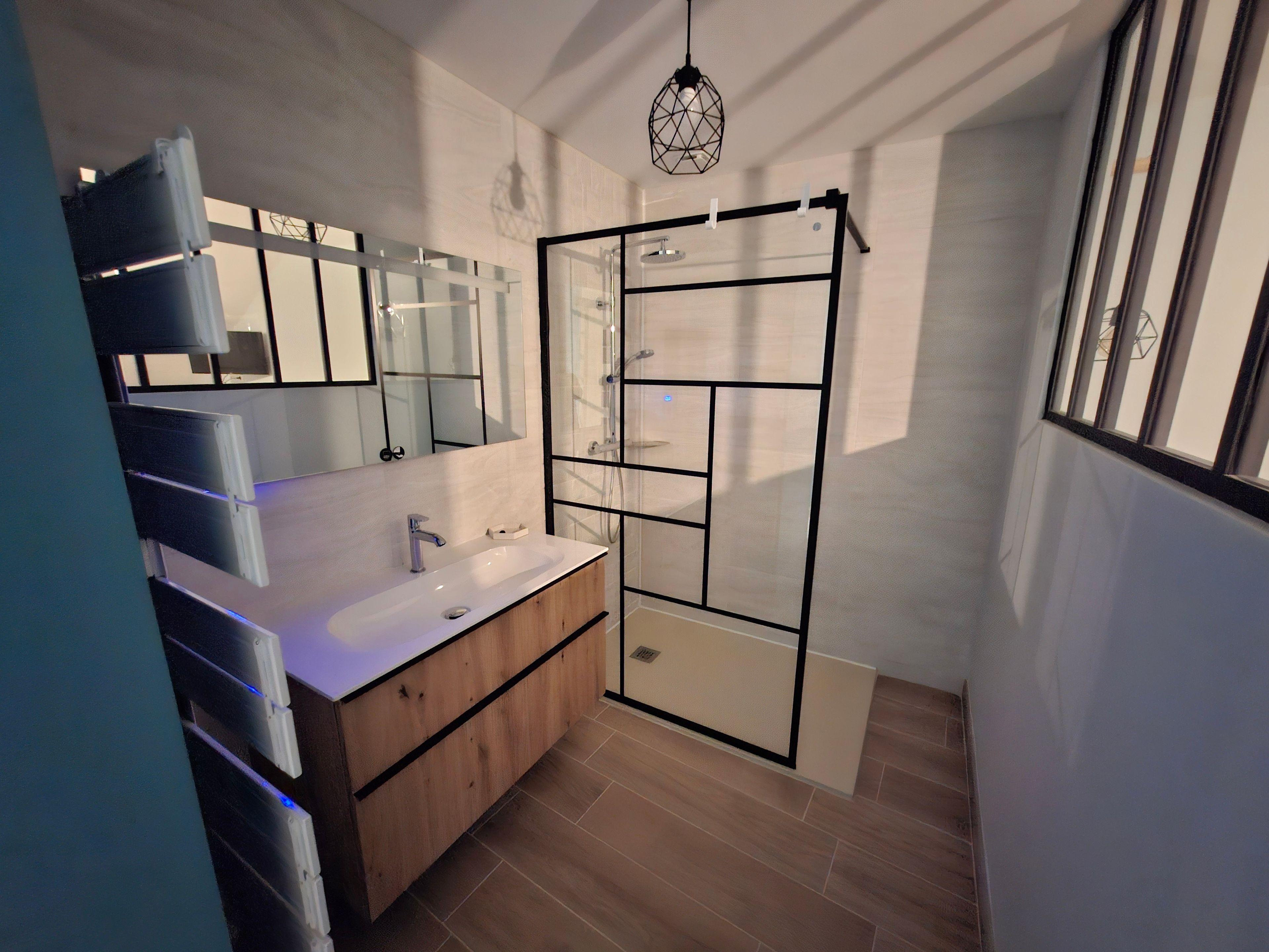 Une salle de bain moderne avec un grand miroir, un lavabo et une cabine de douche.